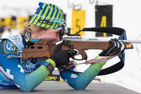 Sportswoman biathlete Anastasia Legostaeva rifle shooting in prone position. Biathlete in shooting