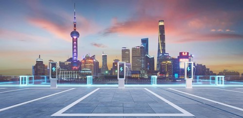 Empty parking lot with ev chargers glowing against the backdrop of the illuminated shanghai skyline