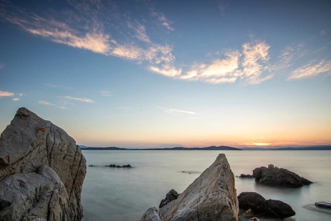 View through rocks on a sandy beach into the sunset. Landscape shot with view to the horizon over