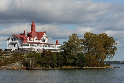 This image captures a historic seaside building with distinctive red roofs, nestled on a small