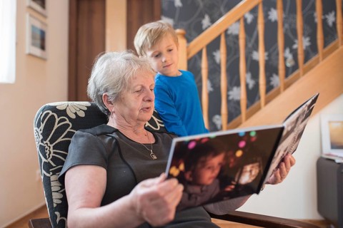Grandmother and grandson watching photo album with the grandson pictures on the cover