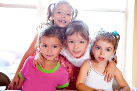 Sister and friends kid girls in hug happy together posing looking camera
