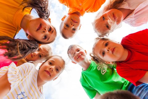 Cute girls and boys in colorful clothes standing together in circle looking at the camera on the