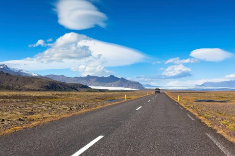 Highway through South Icelandic landscape under a blue summer sky with clouds