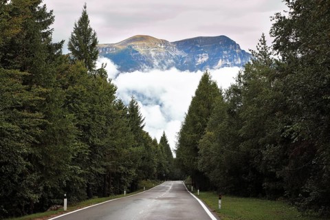 Wet shiny road in the Swiss Alps. Cold autumn day, low cumulus clouds