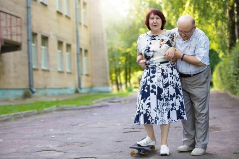 Happy elderly couple with a skateboard. Handsome man and woman seniors. Husband and woman in old