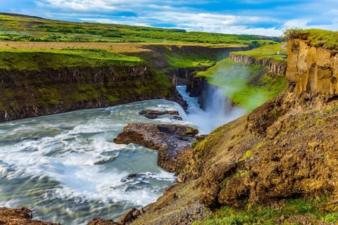 Tundra on a sunny summer day. The waterfall in Iceland - Gullfoss on the Hvitau River. Huge masses