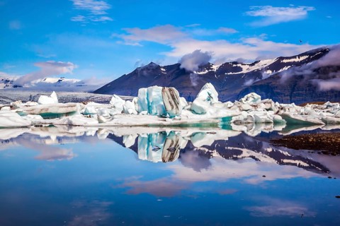 Icebergs and ice floes are reflected in the smooth water surface. Drift ice Ice Lagoon -