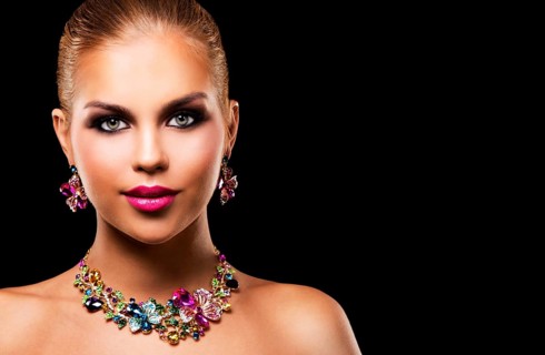 Beautiful woman with dark makeup and pink lipstick posing on black background wearing flower spring