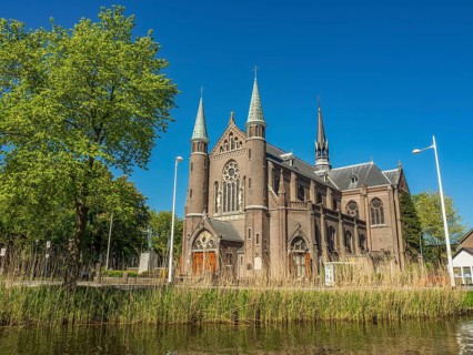 Impressive church with towers and grand architecture, surrounded by trees under a blue sky,