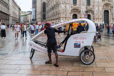 MILAN, ITALY, AUGUST 4, 2021: Street vendor offering bike rides in his covered bicycle taxi in