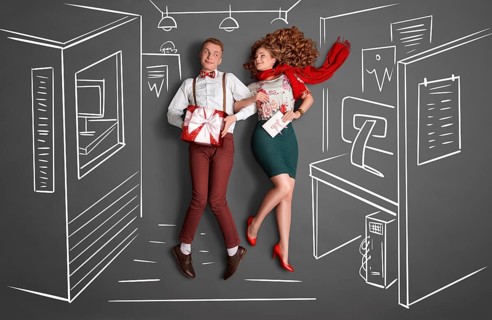 Happy valentines love story concept of an office romance. Young couple at work smiling at each
