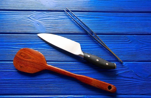 Chef tools knife tweezers and spatula on a blue wooden background