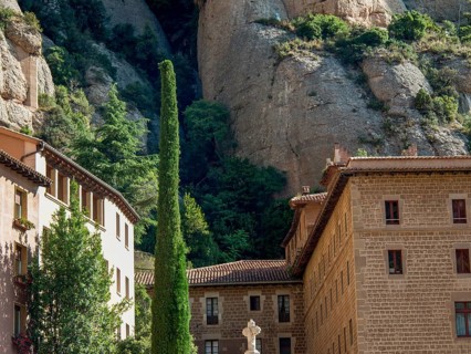 Stone building built against the rocks, surrounded by trees and vegetation, montserrat, spain