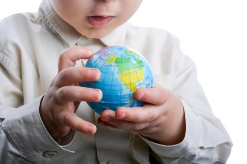 Baby holding a small globe in hand on white background