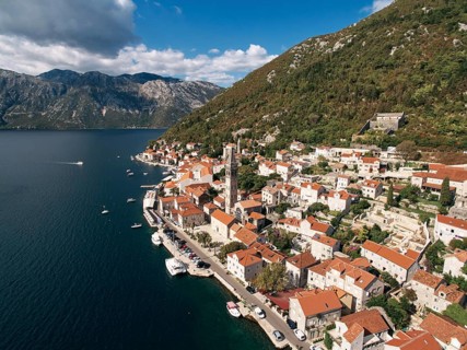 Cars parked on the promenade near the bell tower of the Church of St. Nicholas. Perast, Montenegro.