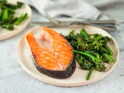 Ready-to-eat grilled salmon steak and greens - baby broccoli or broccolini and spinach on rustic