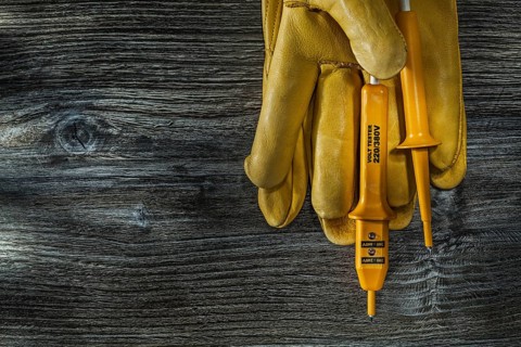 Electric tester leather safety gloves on vintage wooden board