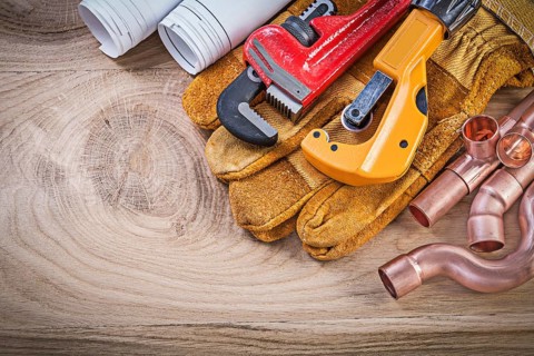 Construction drawings protective gloves monkey wrench pipe cutter fixtures on wooden board plumbing