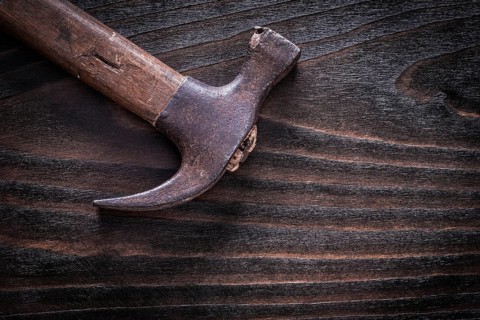 Rusty metal claw hammer on vintage dark wooden board top view construction concept