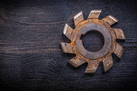 Vintage rotary cutter with cogs on wood board construction concept