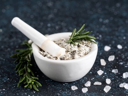 Close up view of mortar and pestle with sea salt scented rosemary and lemon zest. Sea salt scented