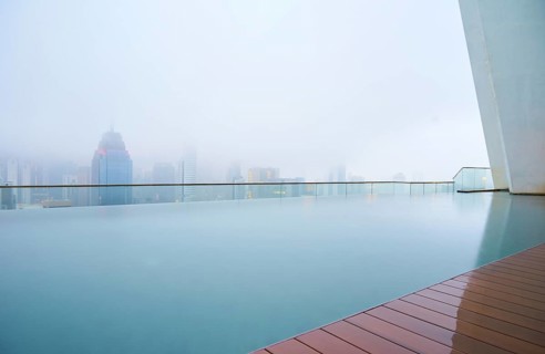 Swimming pool on roof top with beautiful city skyline view, early morning with mist, kuala lumpur