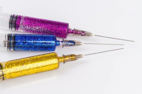Close up of syringes with colorful glitter. Isolated on white