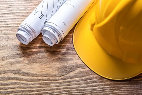 Rolled engineering drawings hard hat on wooden board construction concept