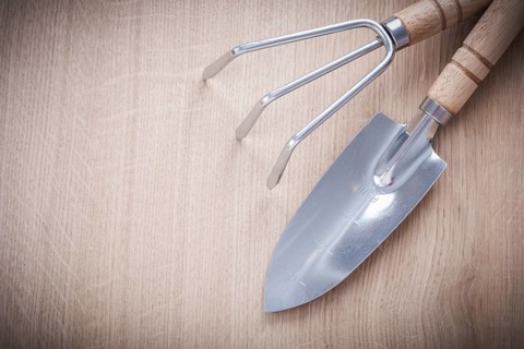 Stainless gardening trowel fork with sharp hand spade on wooden board horizontal version