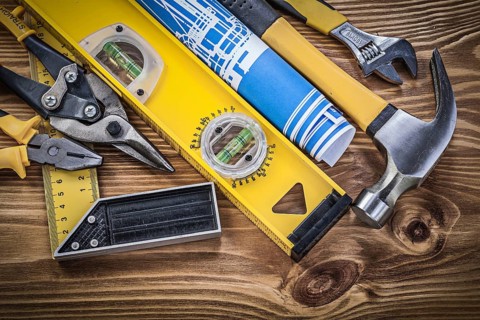 Collection of construction tools on wooden board top view