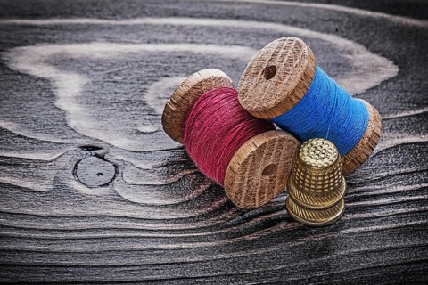 Vintage spools of thread thimbles on wooden board fancy-work concept