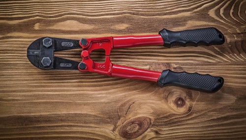 Bolt cutter on vintage wooden board construction concept