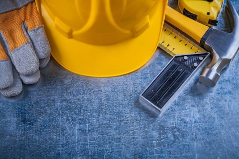 Square ruler safety gloves tape-measure building helmet and claw hammer on scratched metallic