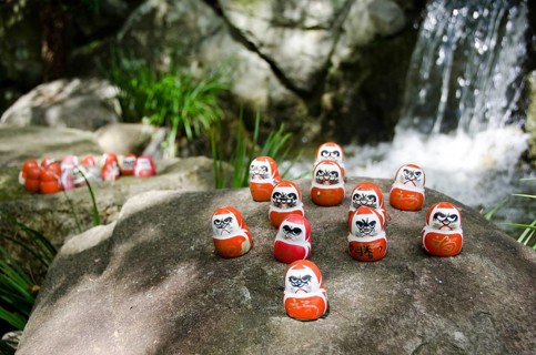 Traditional japanese Daruma dolls in front of a water fall at Katsuo Ji Temple in Mino, Japan,