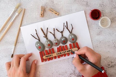 Diy Merry Christmas deer on greeting card postcard made of pebbles, sea stones, clothespins and