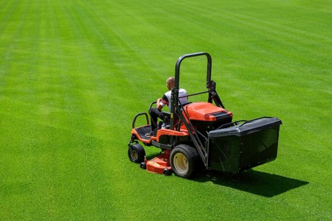 Mowing grass at the football stadium in Lubin, Poland, Europe