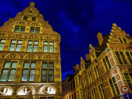 Two illuminated historical buildings at night, glowing in blue light. Cloudy sky, Ghent, Belgium,