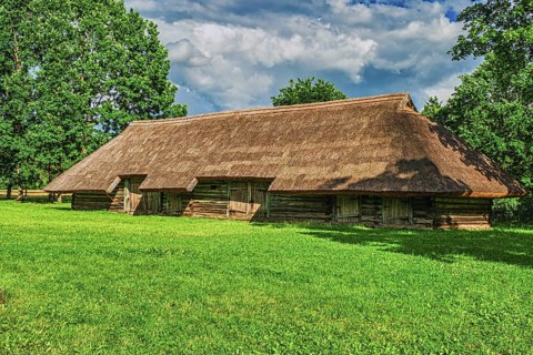 Old Wooden Barn with Green Grass and Blue Sky Background