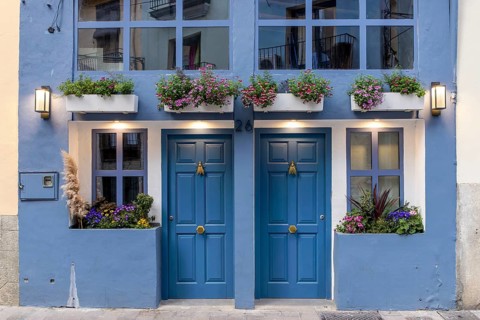 Detail of a building with a blue façade and two symmetrically arranged doors and windows, richly