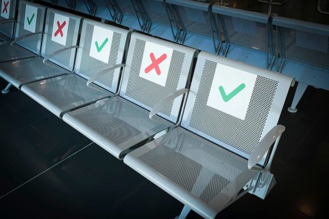 Empty chairs on an airport terminal with signs to keep social distance for the preventions of