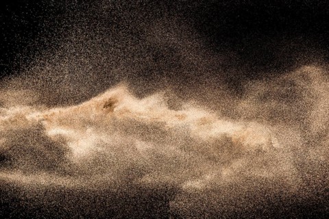 Dry river sand explosion. Golden colored sand splash against black background