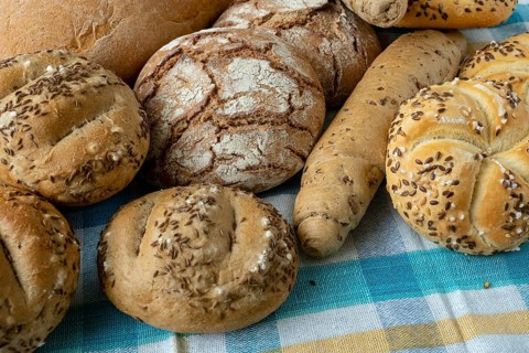 Heap of various bread rolls sprinkled with salt, caraway and sesame. Fresh rustic bread from