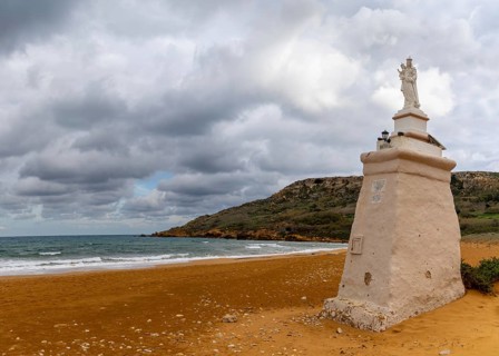 Ramla Bay, Malta, 20 December, 2023: view of the red sand beach and Staue of Our Lady in Ramla Bay