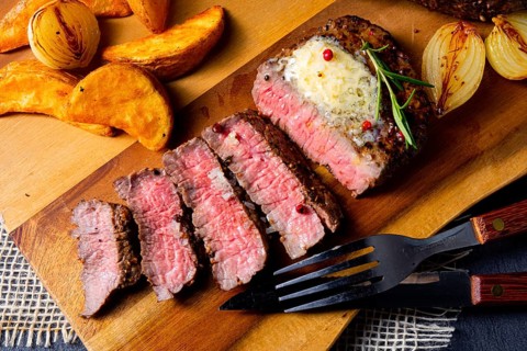 Rustic medium rare beef steak with herbs and potato wedges