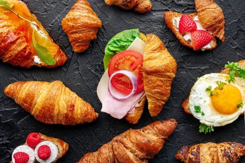 Croissant sandwich assortment. Many stuffed croissants, overhead flat lay shot on a black slate