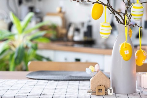 Key to house of cozy home with Easter decor with rabbit and eggs on table of kitchen. Building,