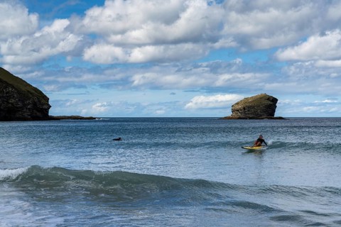 Portreath, United Kingdom, 4 September, lifeguard riding a wave on her emergency rescue board at