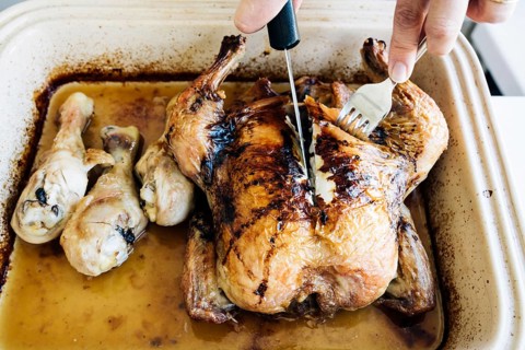 Woman carving homemade whole roasted chicken on plate