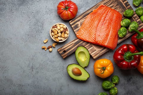 Fresh raw salmon fillet on wooden cutting board, organic bio vegetables and nuts on rustic stone